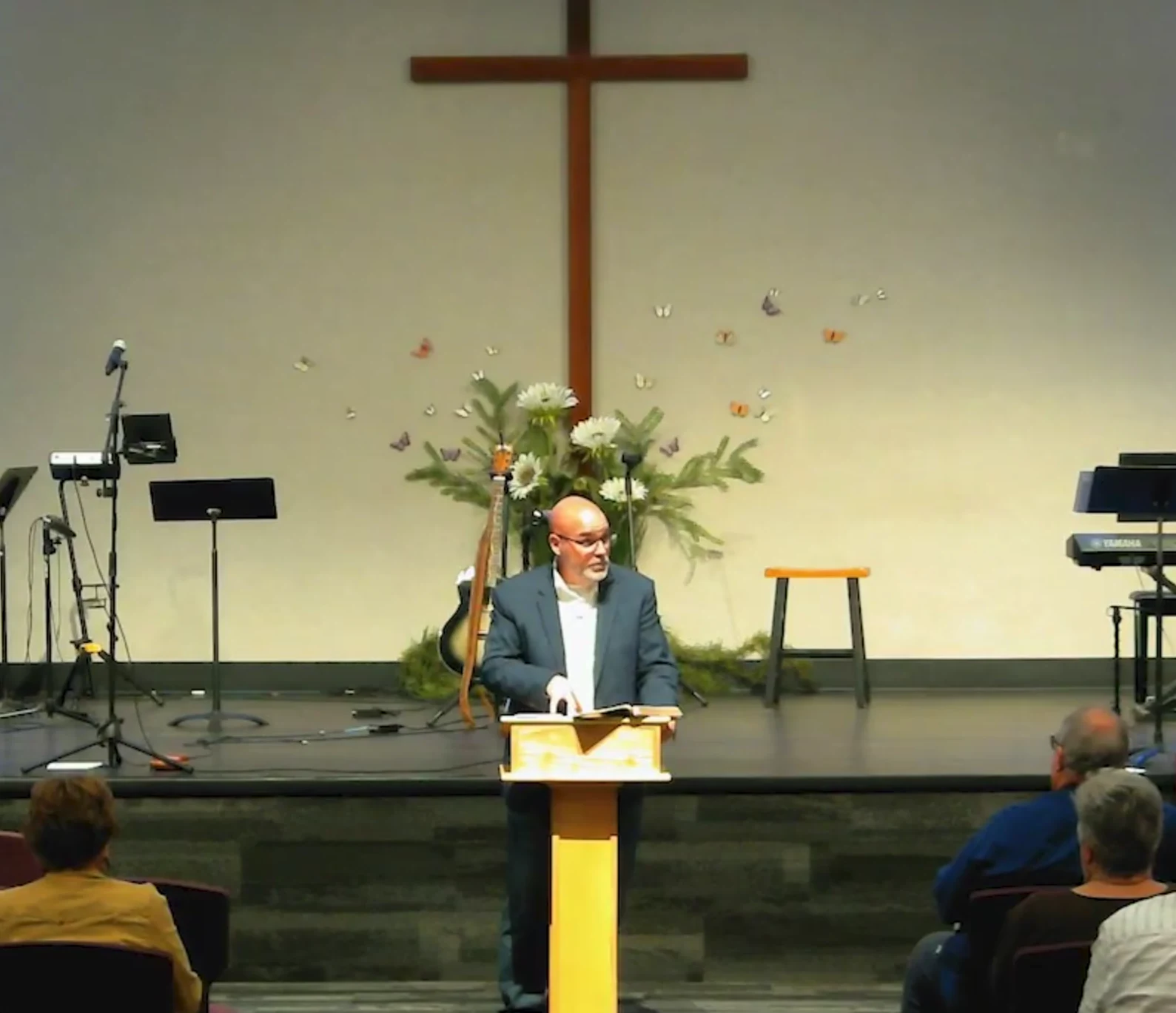 Pastor preaching at Pleasant View Missionary Church, with the cross behind him